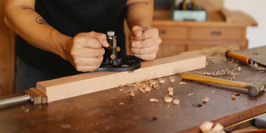 Ремісник в майстерні обробляє дерев'яну деталь.
